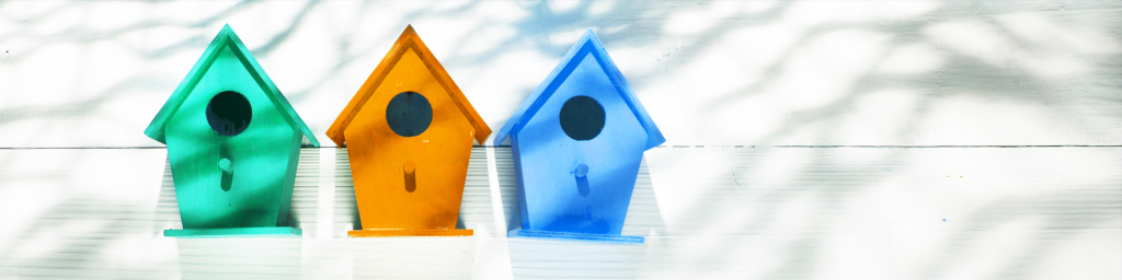 three colourful birdhouses against a white background